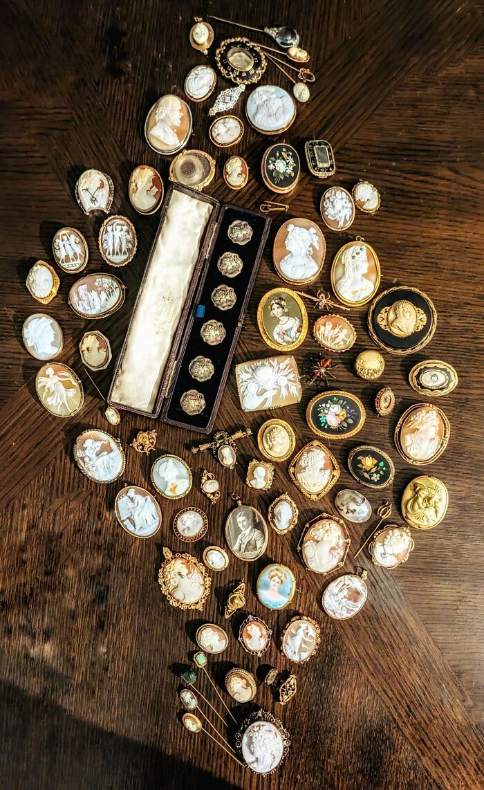 Collection of beautiful old cameos and vintage brooches displayed on a wooden surface, showcasing interesting old things.