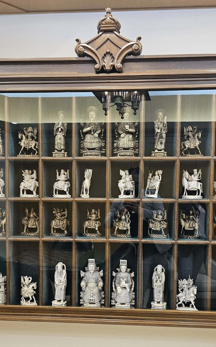 Collection of beautiful old antique figurines displayed in a wooden cabinet, showcasing intricate craftsmanship and historical charm.