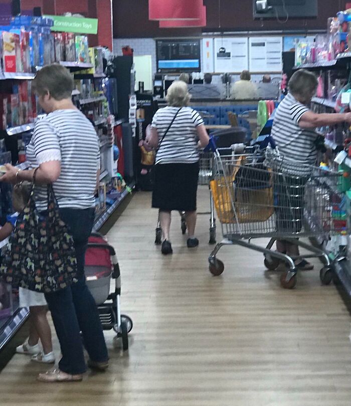 Three women wearing the same striped shirt in a store aisle, creating a real-life glitch in the matrix moment.