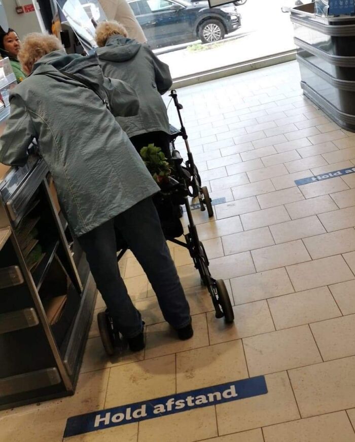 Two identical elderly people in similar jackets creating a real-life glitch in the matrix moment while shopping.