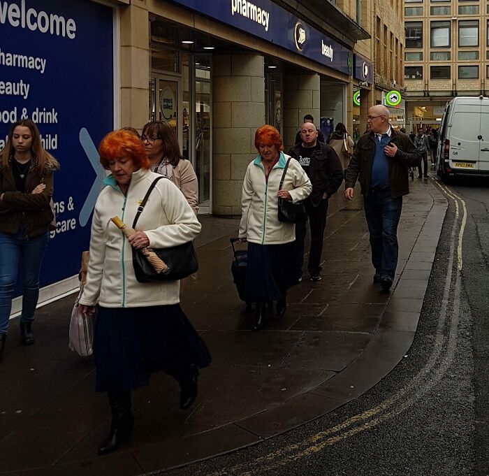 Two identical women walking side by side on a street, illustrating real-life glitches in the matrix phenomenon.