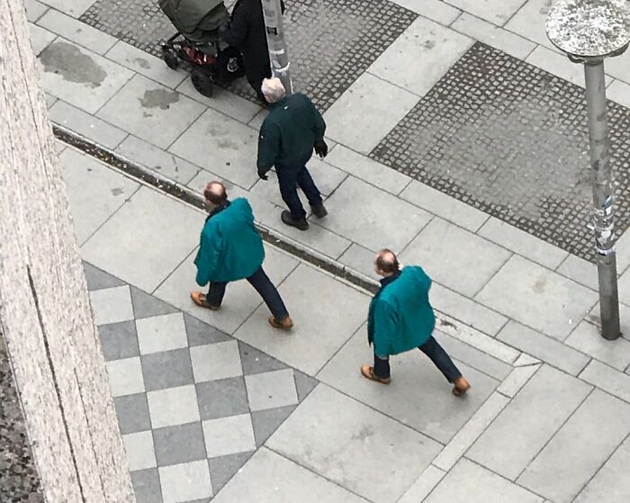 Two identical men in teal jackets walking on a sidewalk, capturing real-life glitches in the Matrix moment.