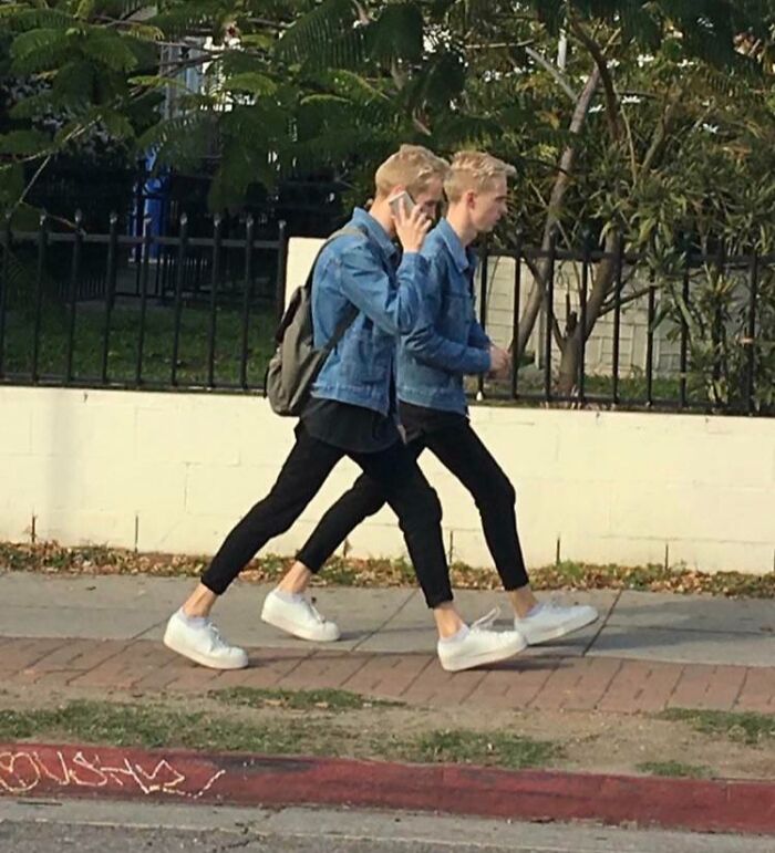 Two identical men in denim jackets walking side by side, creating a real-life glitch in the matrix moment.