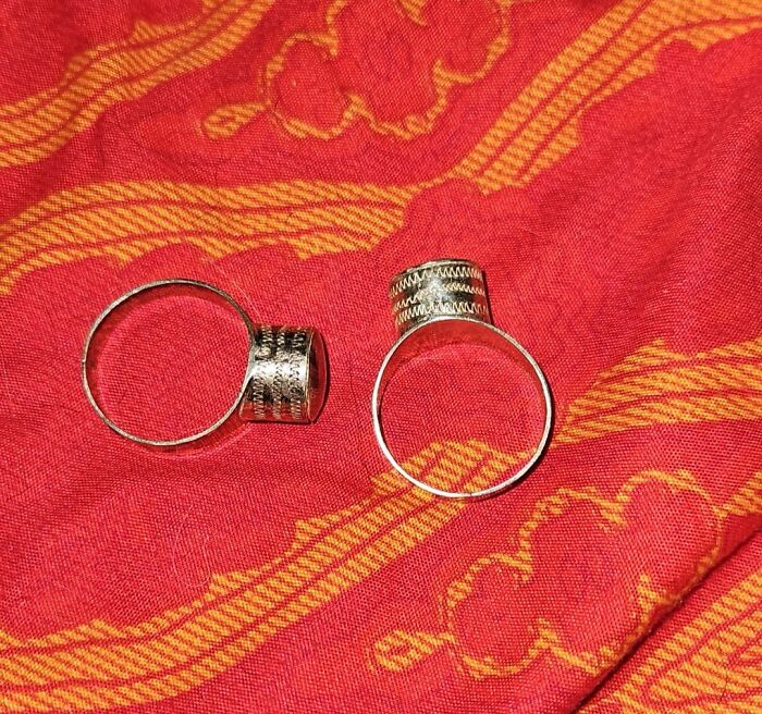 Two identical silver rings placed on a patterned red fabric, illustrating a real-life glitch in the matrix.