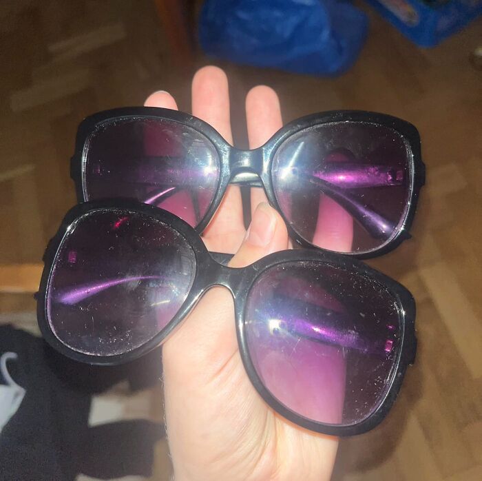 Two pairs of sunglasses held in one hand, showing a real-life glitch in the matrix phenomenon with reflections.