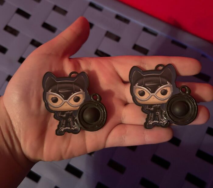 Two identical Catwoman keychains held in one hand, showing a real-life glitch in the matrix moment.