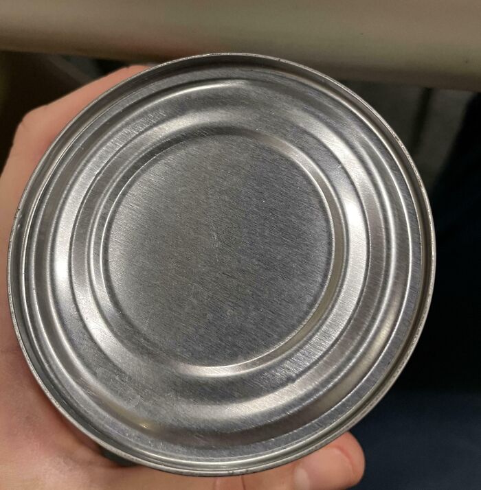 A person holding a metal can with no label, showing a funny unfortunate situation of forgetting something important.