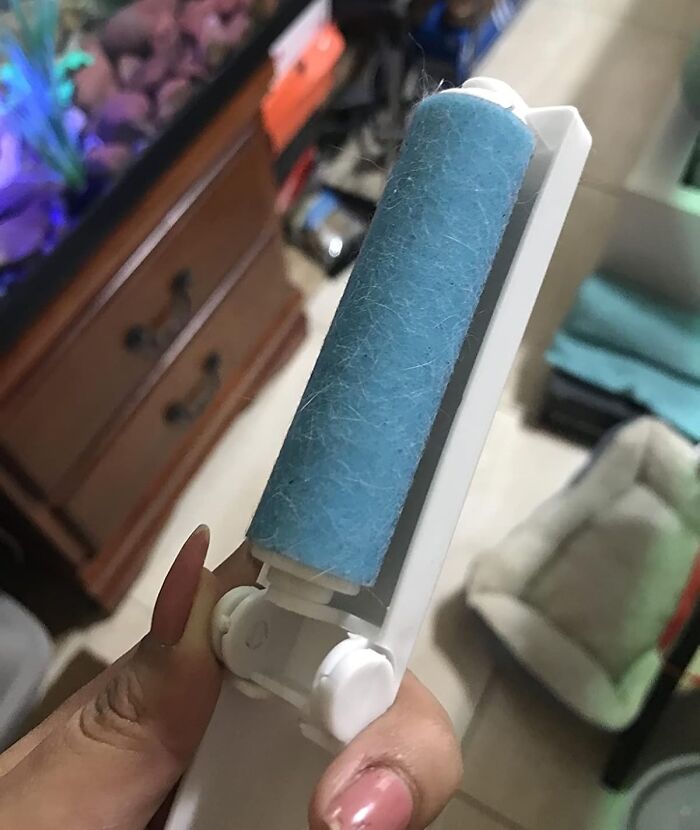 Hand holding a lint roller covered in pet hair showing one of the random things surprisingly useful for cleaning.