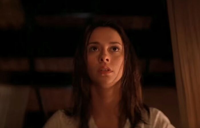 Young woman with wet hair looking up in a dimly lit room, illustrating cinematic crimes in worst movie sequels.