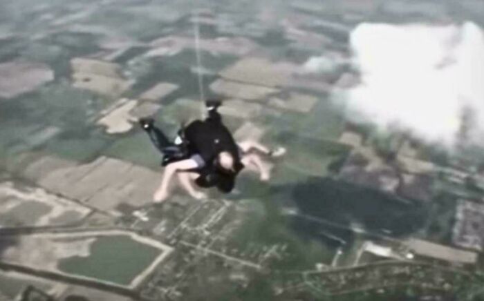 Two people tandem skydiving above fields demonstrating unusual and cool world facts in action.