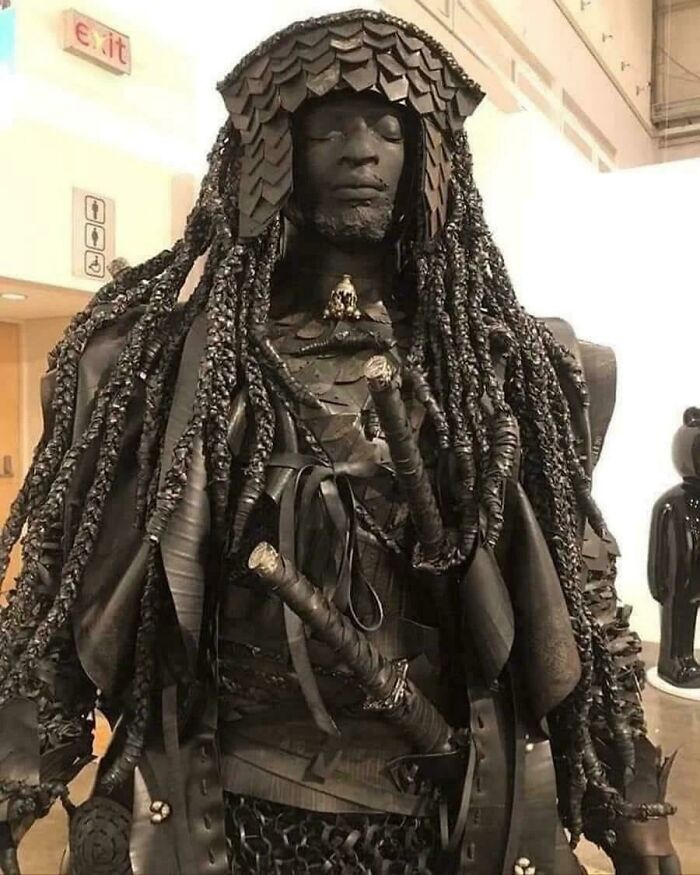 Sculpture of a warrior with braided hair and armor made of unusual materials, showcasing cool world facts.
