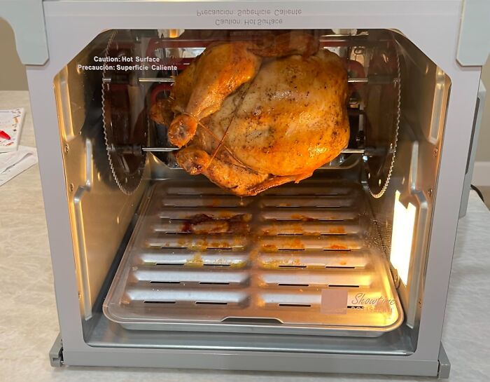 Rotisserie oven cooking a golden brown chicken, showcasing a popular infomercial find for home use.