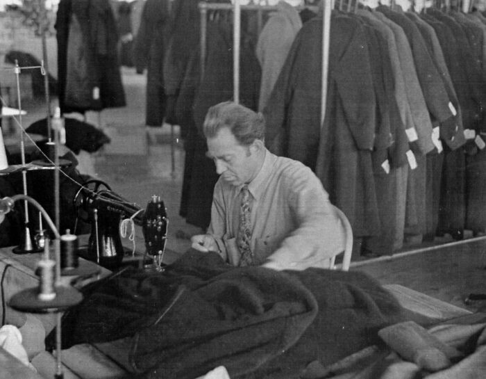 Man sewing coats in a factory, a rare photo capturing the Great Depression era work environment and clothing production.