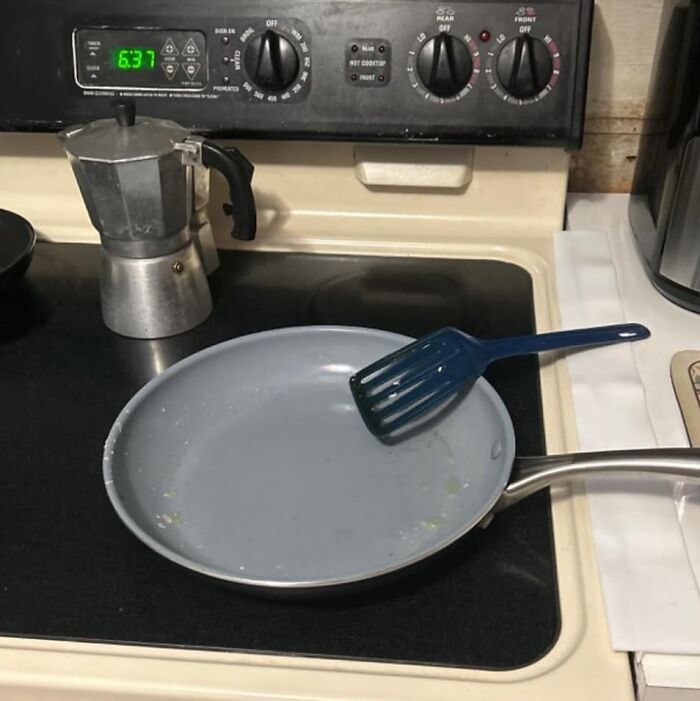 Blue spatula resting on a gray frying pan on a stove, showing everyday infomercial finds people use at home.