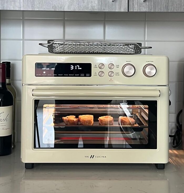 Retro cream-colored toaster oven baking muffins on kitchen counter, showcasing vintage-inspired retro finds for old soul enthusiasts.