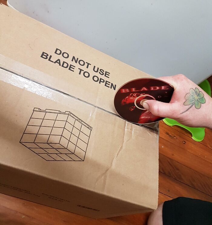 Person using a Blade movie disc to open a box labeled do not use blade to open, showing suspiciously unbothered attitude.