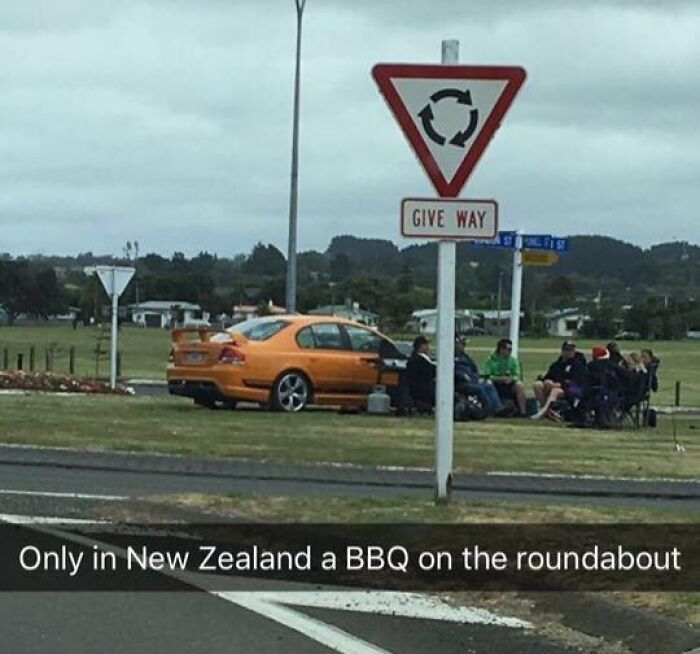 Group having BBQ on a grassy roundabout in New Zealand, showing suspiciously unbothered attitude in public space.