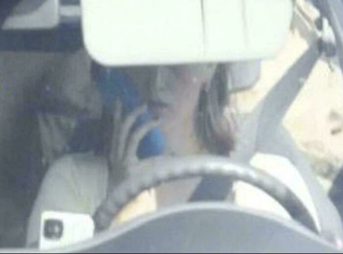 Person driving car while using a phone, illustrating unusual and cool world facts about distracted driving safety.