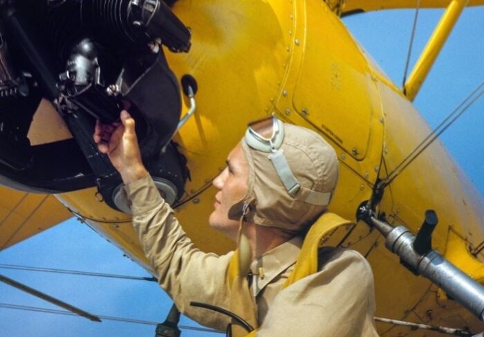 Woman worker inspecting airplane engine during WWII, showcasing the bold and brilliant world of women at work.