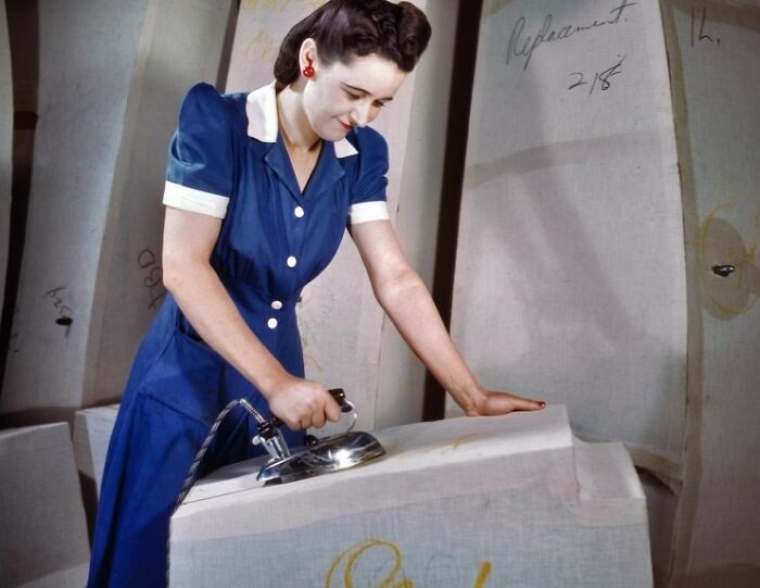 A woman in a blue dress working with an iron, representing women at work during WWII in a bold, brilliant world.