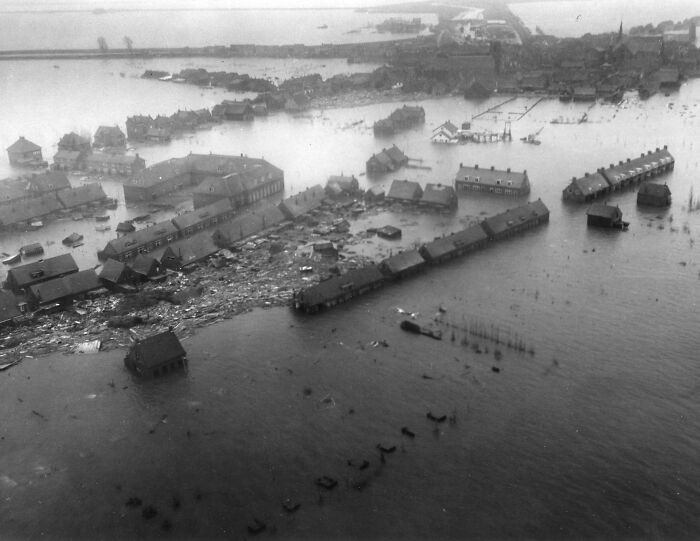Aerial view of severe flooding causing damage to homes and streets during a major natural disaster in the last century.