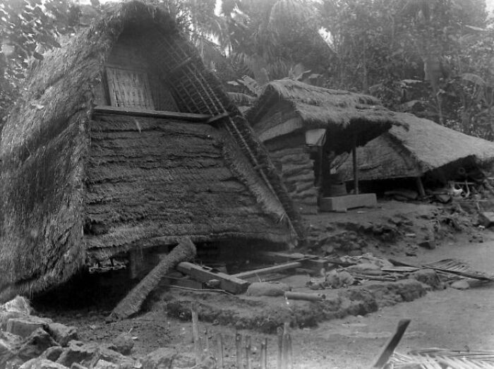 Thatched huts damaged by a natural disaster, illustrating the scale of natural disasters larger than people could cope with.