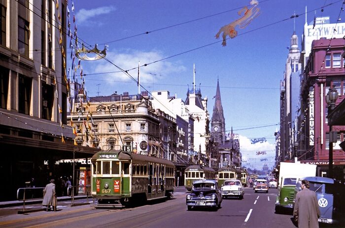 1950s daily life captured with vintage trams, classic cars, and pedestrians on a bustling city street scene.