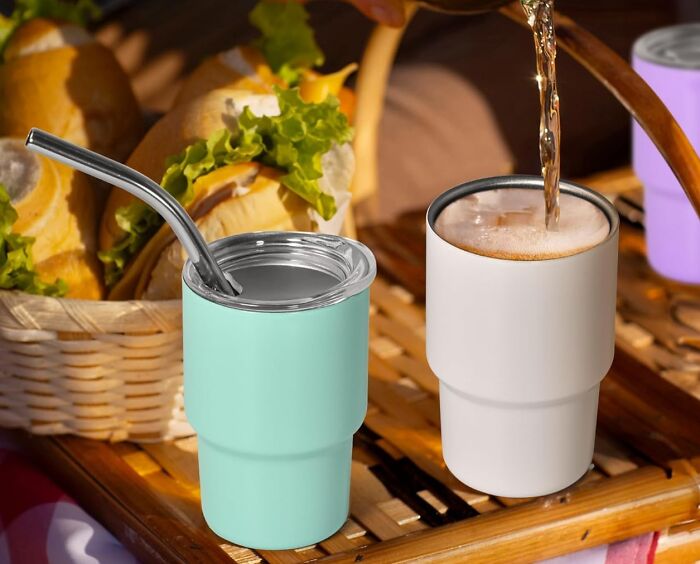 Two insulated tumblers on a picnic tray with a straw and drink being poured, perfect cool gifts for summer.