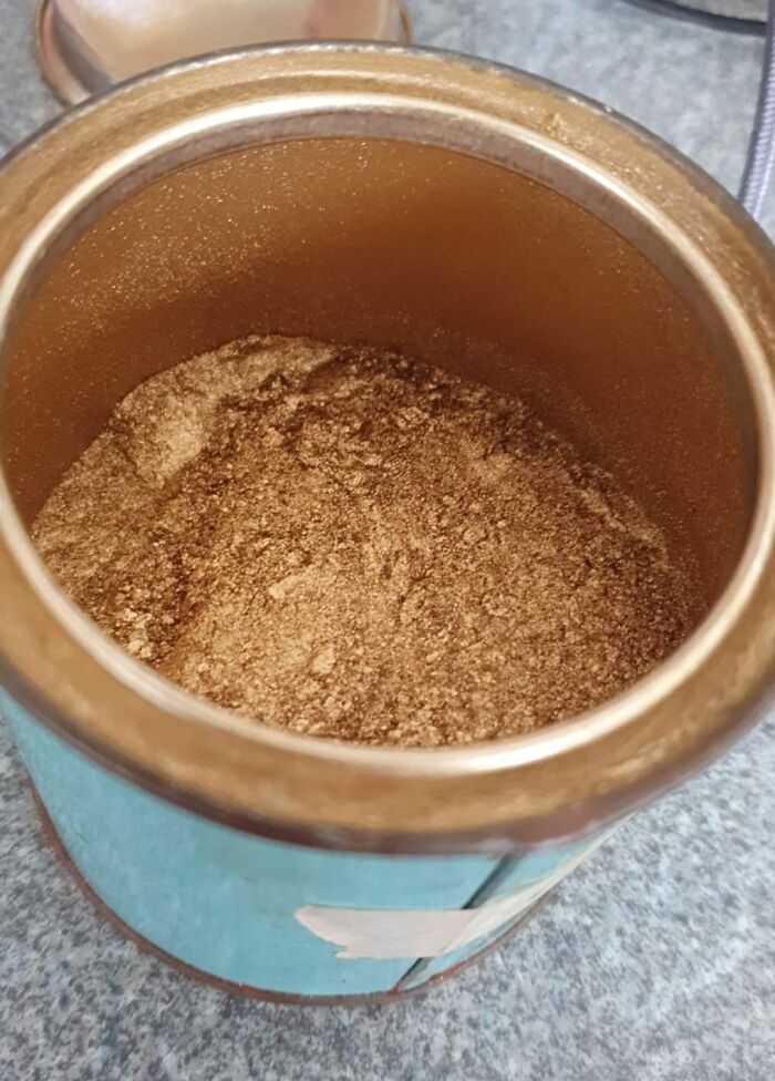 Close-up of a container filled with brown powder, part of surprising fossil discoveries under the floor boards in old homes.