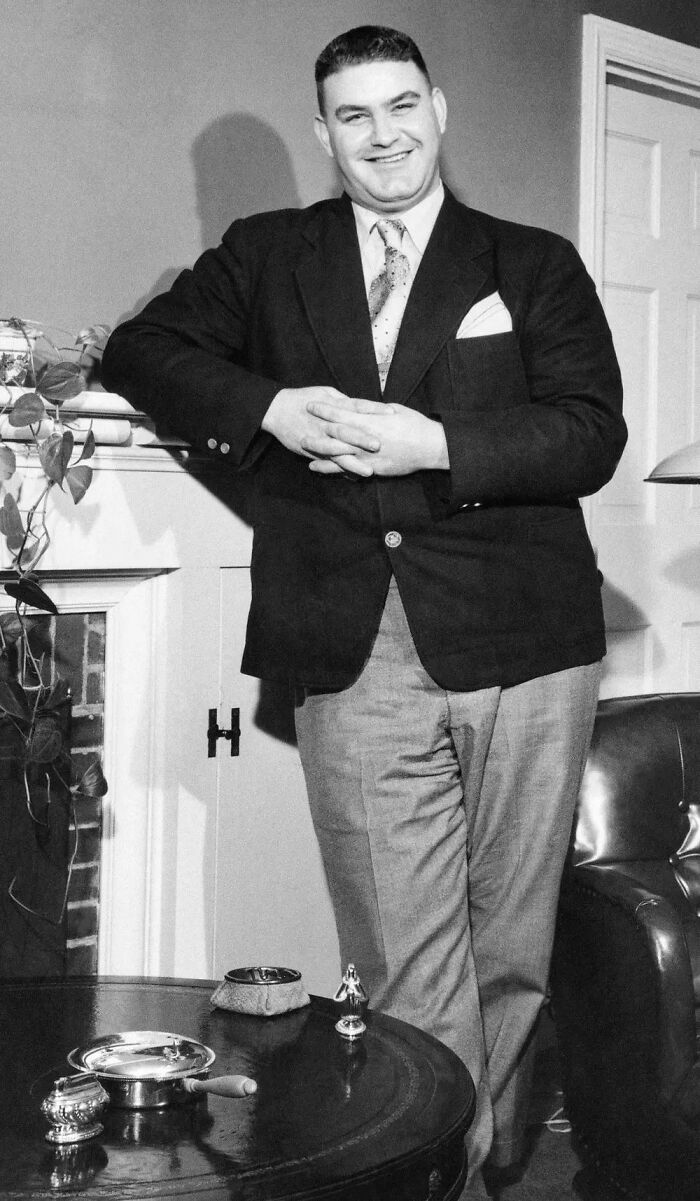Man standing and smiling in a suit indoors, vintage medical photos highlighting extraordinary medical conditions.