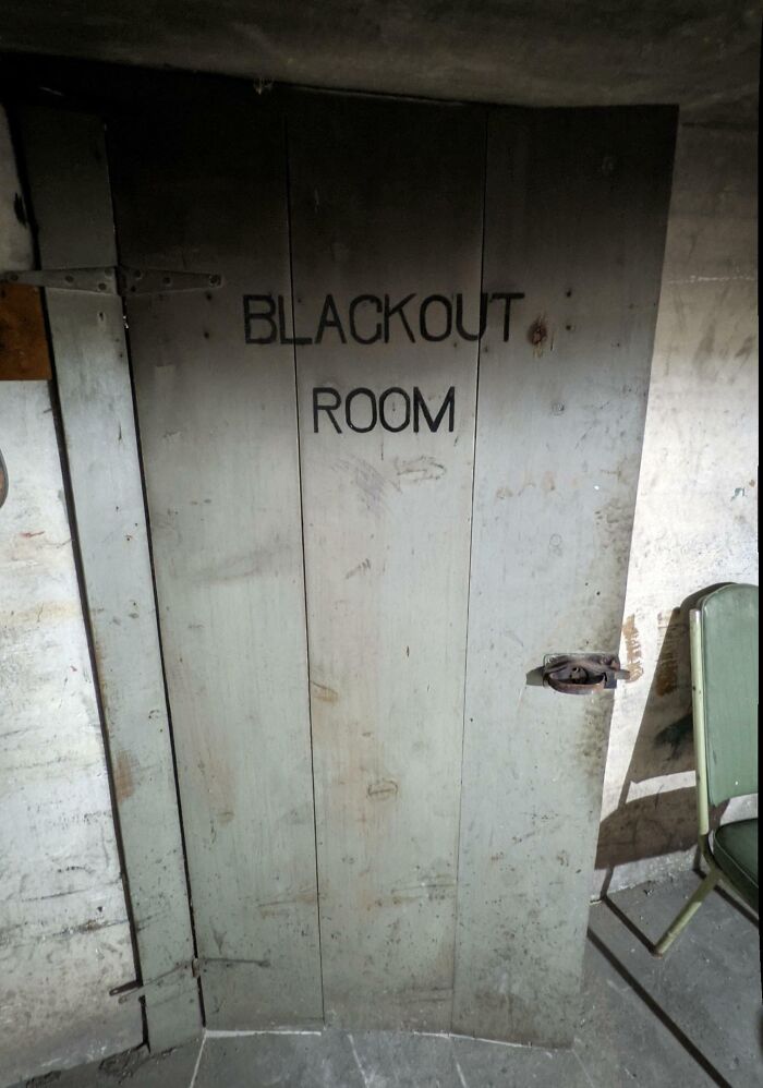 Old wooden door marked blackout room in a dimly lit, dusty basement of an old home finding.