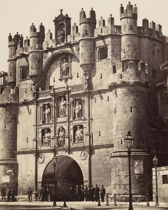 Historic stone gate with intricate sculptures and cylindrical towers showcasing old architecture and past beauty.