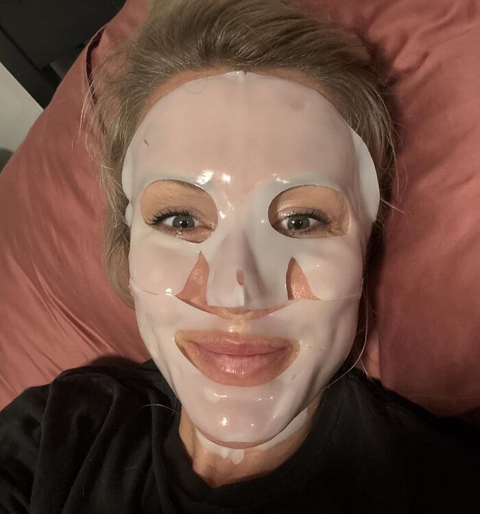 Woman wearing a hydrating face mask relaxing on a bed, featuring one of the best sellers from Prime Day skincare products.