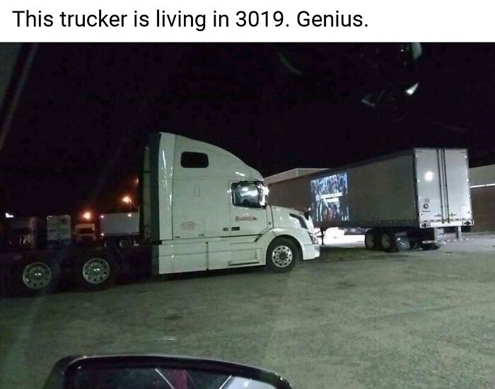 A white truck is projecting a movie onto its trailer at night, showcasing one of the weird internet moments captured.