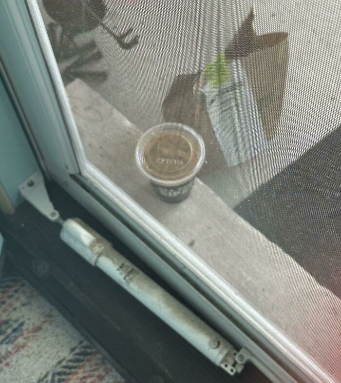 Small package and coffee cup left outside a door on a porch, showing a delivery that went off track.