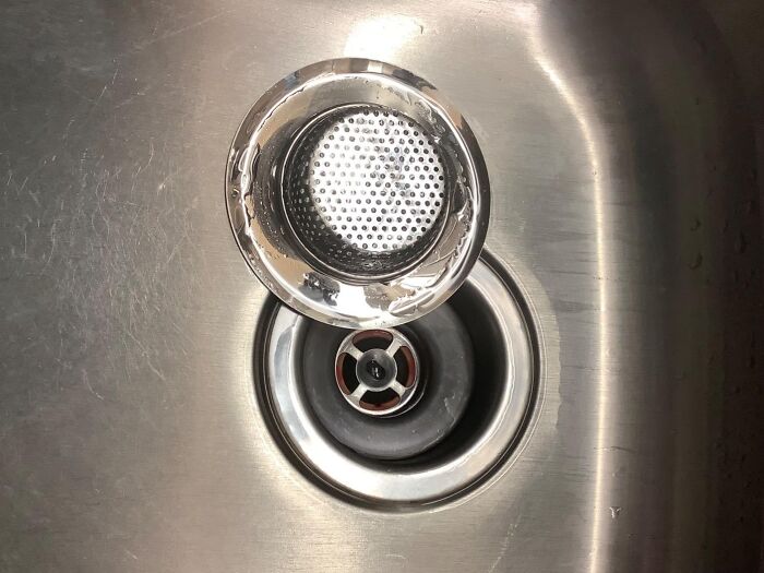 Stainless steel kitchen sink with a removable strainer drain showing a clever home hack for organization.