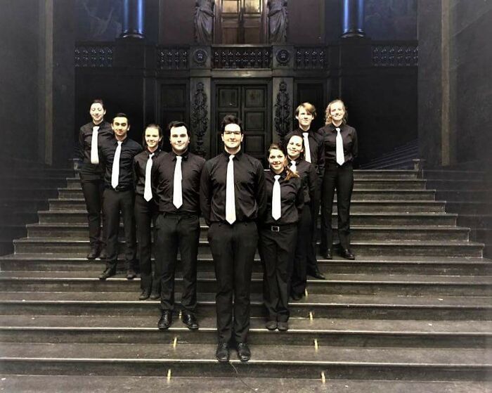 Group of people dressed in black with white ties standing on steps, showcasing imperfect alignment that may annoy those with OCD