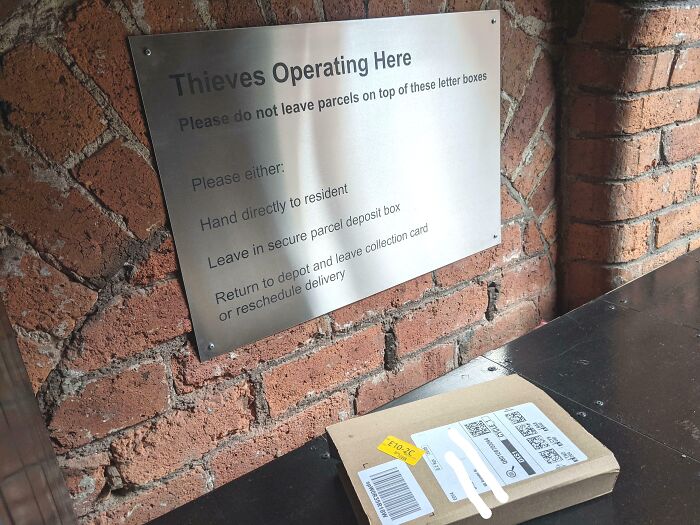 Metal sign warning of thieves operating here next to a misplaced package showing delivery off track and risk of theft.
