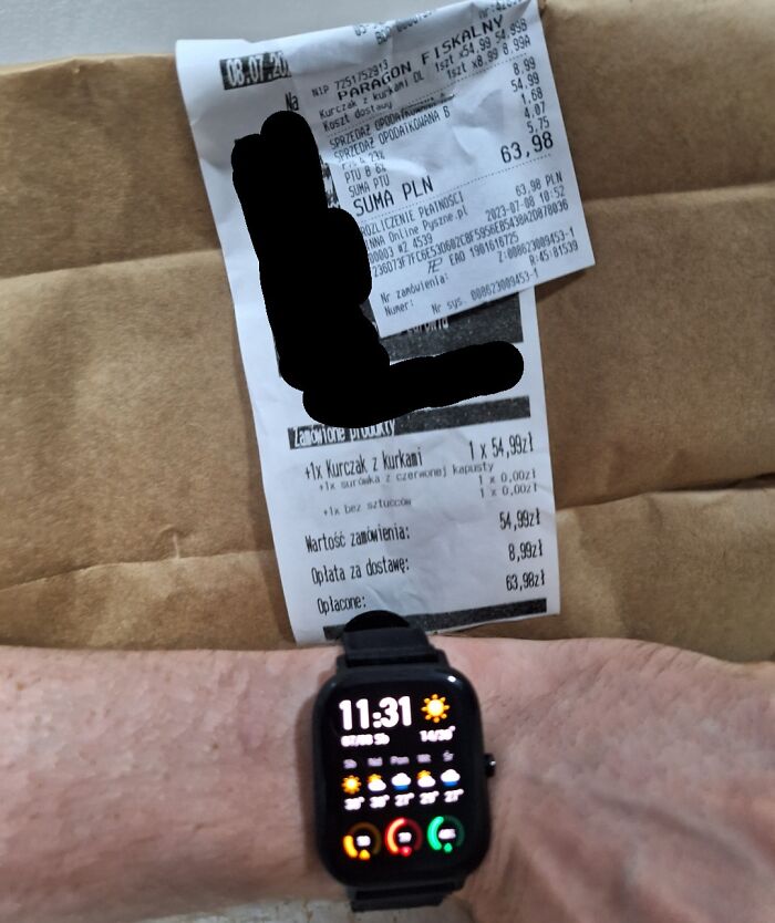 Receipt for a delayed delivery shown on a brown package with a smartwatch displaying the time on a person's wrist.