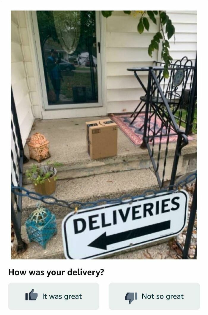Small delivery package placed awkwardly behind a deliveries sign on a front porch with stairs and railings.