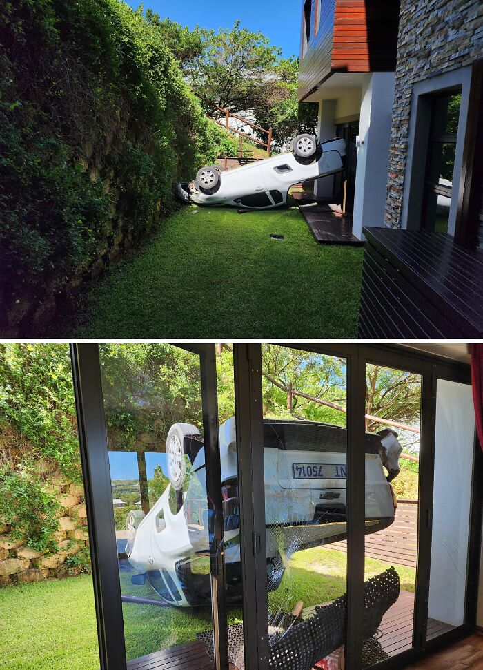 White car overturned outside a house with a broken glass door, showing a dramatic delivery mishap off track.