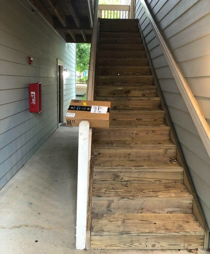 Package precariously placed on stair railing outside an apartment, illustrating delivery mishaps and package delivery issues.