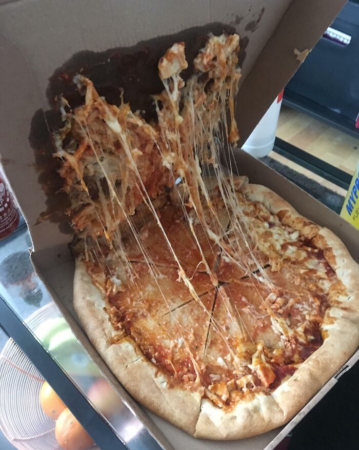 Pizza with melted cheese stuck to the inside of a delivery box, showing an unfortunate delivery fail moment.