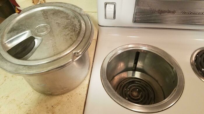 Vintage 1950s kitchen scene with a metal pot on counter next to an old-fashioned electric stovetop burner.