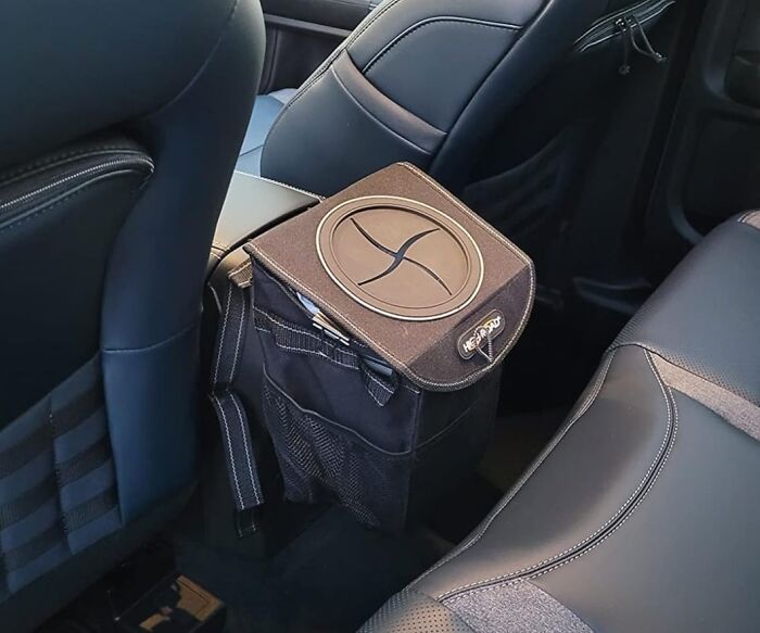 Compact black car accessory trash bin installed beside passenger seat for organized storage and clutter-free interior.
