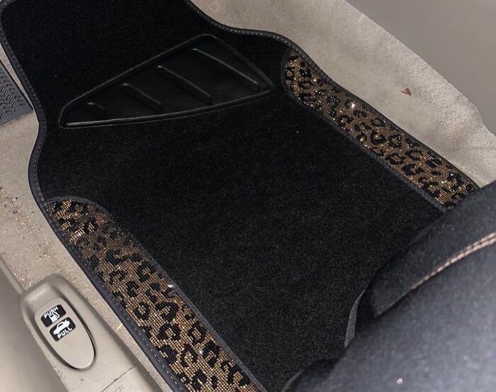 Car accessories featuring a black floor mat with leopard print trim installed on a passenger seat storage area.