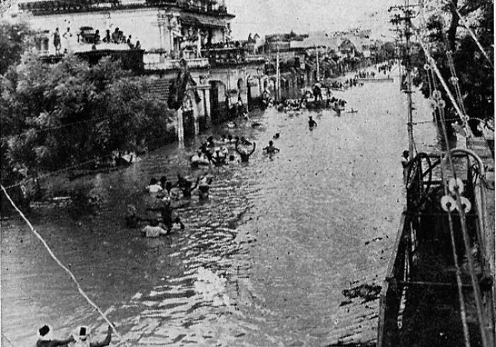 Flooded urban area with people wading through water during one of the largest natural disasters in the last century.