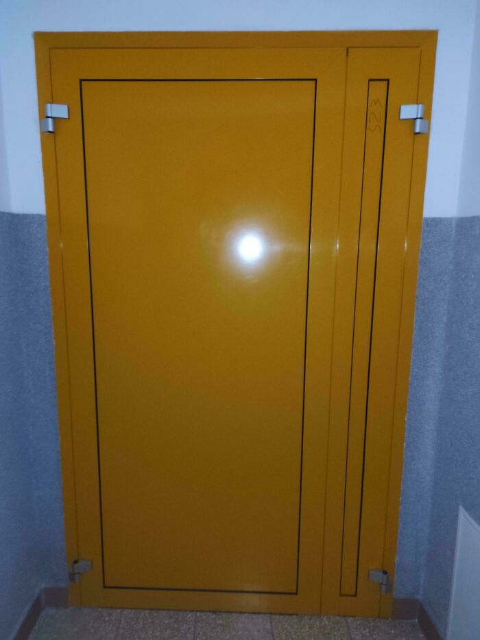 Yellow metal door in a school hallway illustrating how not all schools are created equal in facilities and design quality.