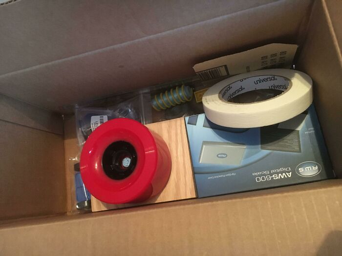 Box with various items including a red object and masking tape illustrating school equipment in unequal schools context