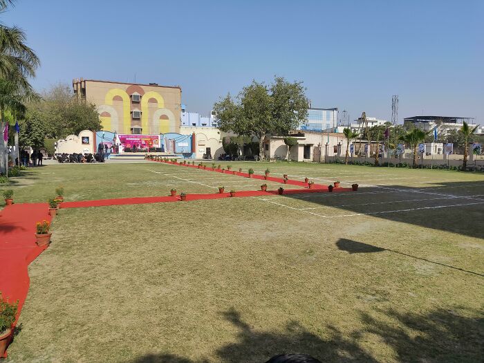 School outdoor area with red carpet and potted plants under clear blue sky showing varied school facilities.
